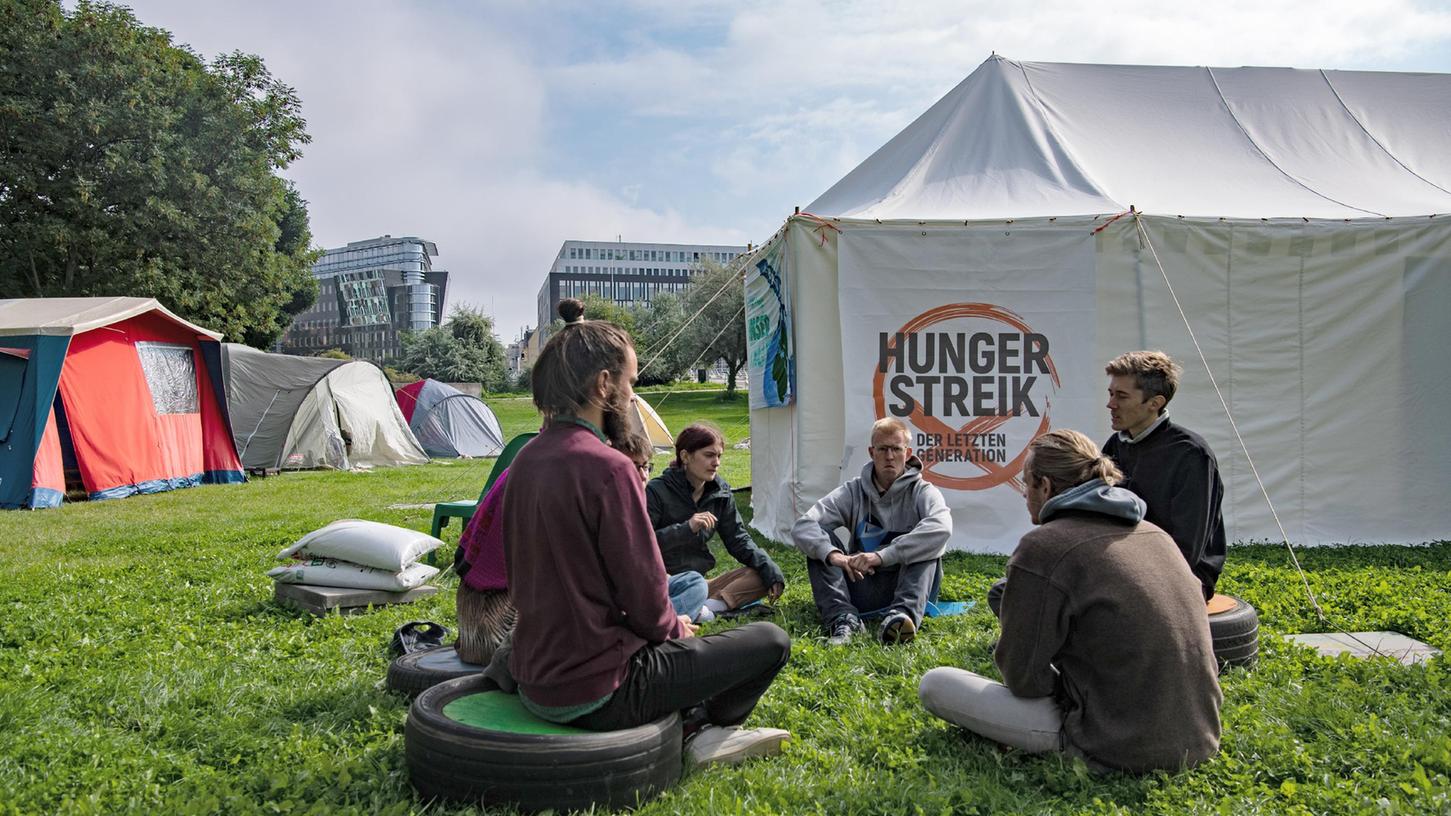 Umweltaktivisten sitzen im Regierungsviertel zusammen vor einem Zelt. 