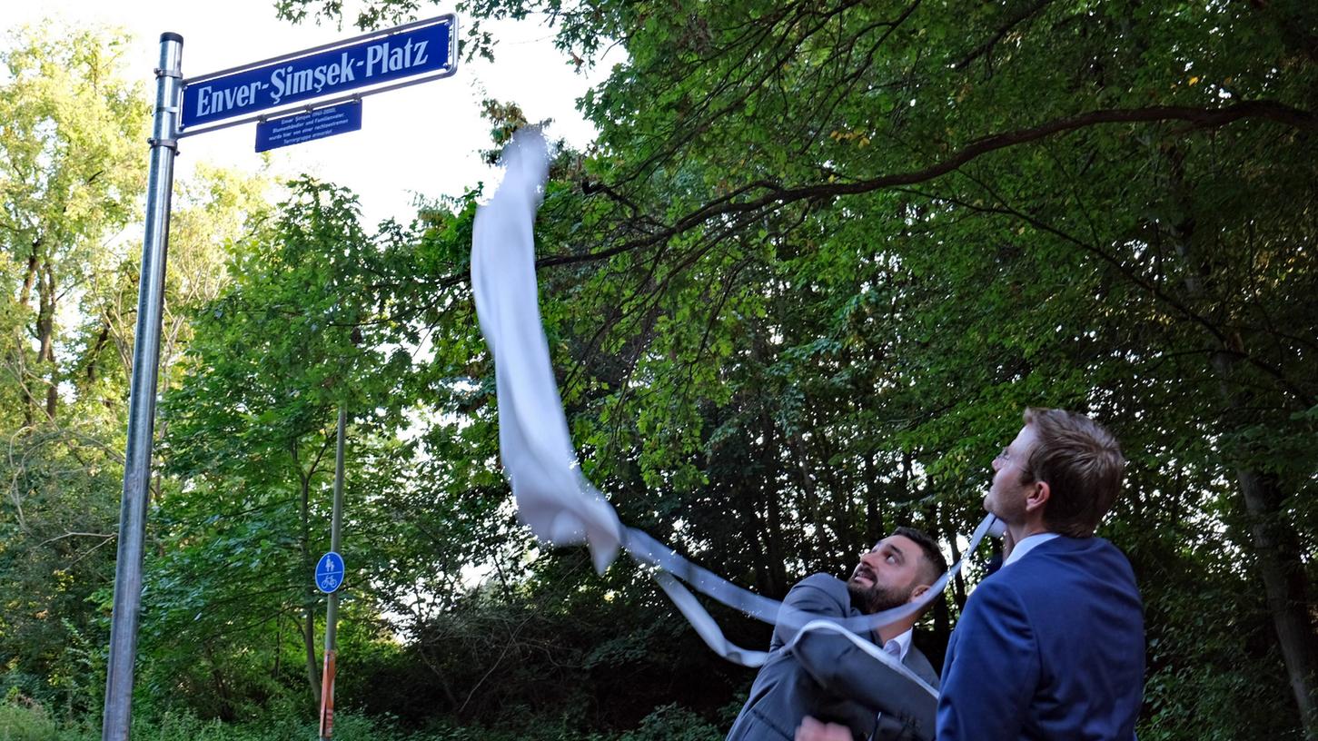 Sohn Abdulkerim Şimşek und Oberbürgermeister Marcus König (von links nach rechts) enthüllen das neue Schild.

