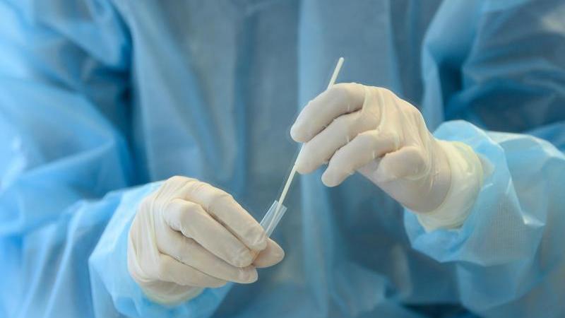 Eine medizinische Mitarbeiterin entnimmt eine Nasenabstrichprobe für einen Coronatest.
