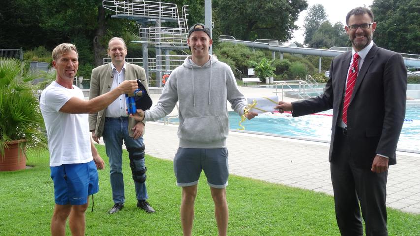 Benjamin Wegler, ein begeisteter Schwimmer und Hobbytriathlet, erwartete bei seinem jüngsten Freizeitbadbesuch eine echte Überraschung: Werkleiter Dr. Gerhard Brunner (2. von links), Bürgermeister Ralph Edelhäußer (rechts) und Badbetriebsleiter Matthias Schubert empfingen ihn als den offiziell 60.000. Besucher dieser Saison mit kleinen Präsenten.
Benjamin Wegler, ein begeisteter Schwimmer und Hobbytriathlet, erwartete bei seinem jüngsten Freizeitbadbesuch eine echte Überraschung: Werkleiter Dr. Gerhard Brunner (2. von links), Bürgermeister Ralph Edelhäußer (rechts) und Badbetriebsleiter Matthias Schubert empfingen ihn als den offiziell 60.000. Besucher dieser Saison mit kleinen Präsenten.