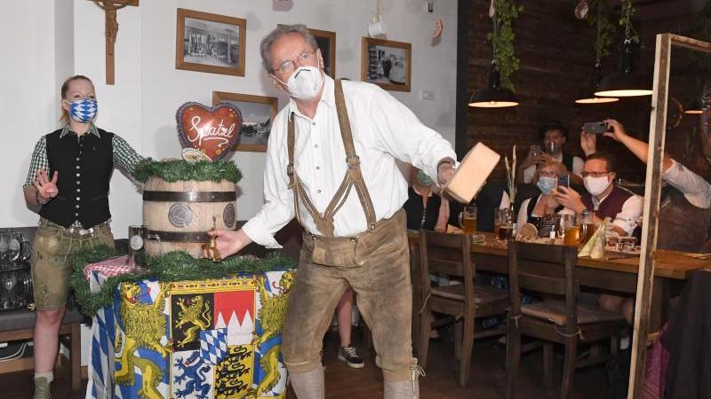 Der ehemalige Münchner Oberbürgermeister Christian Ude zapft mit Mundschutz ein Bierfass an.
Der ehemalige Münchner Oberbürgermeister Christian Ude zapft mit Mundschutz ein Bierfass an.