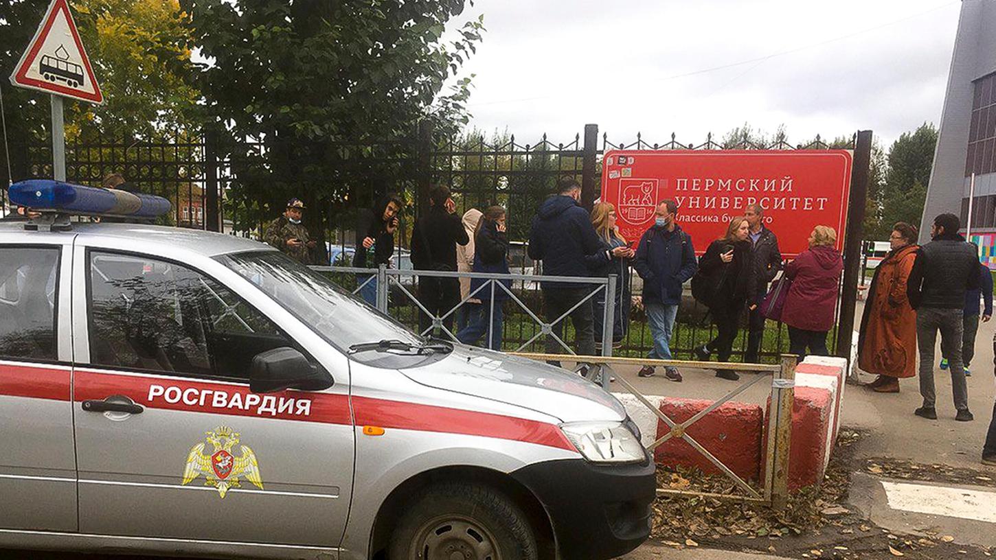 Menschen stehen hinter dem Zaun in der Nähe der Staatlichen Universität Perm.
Menschen stehen hinter dem Zaun in der Nähe der Staatlichen Universität Perm.