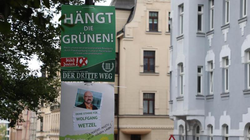 Ein umstrittenes Wahlplakat der Splitterpartei "III. Weg" hängt über einem Plakat der Grünen.