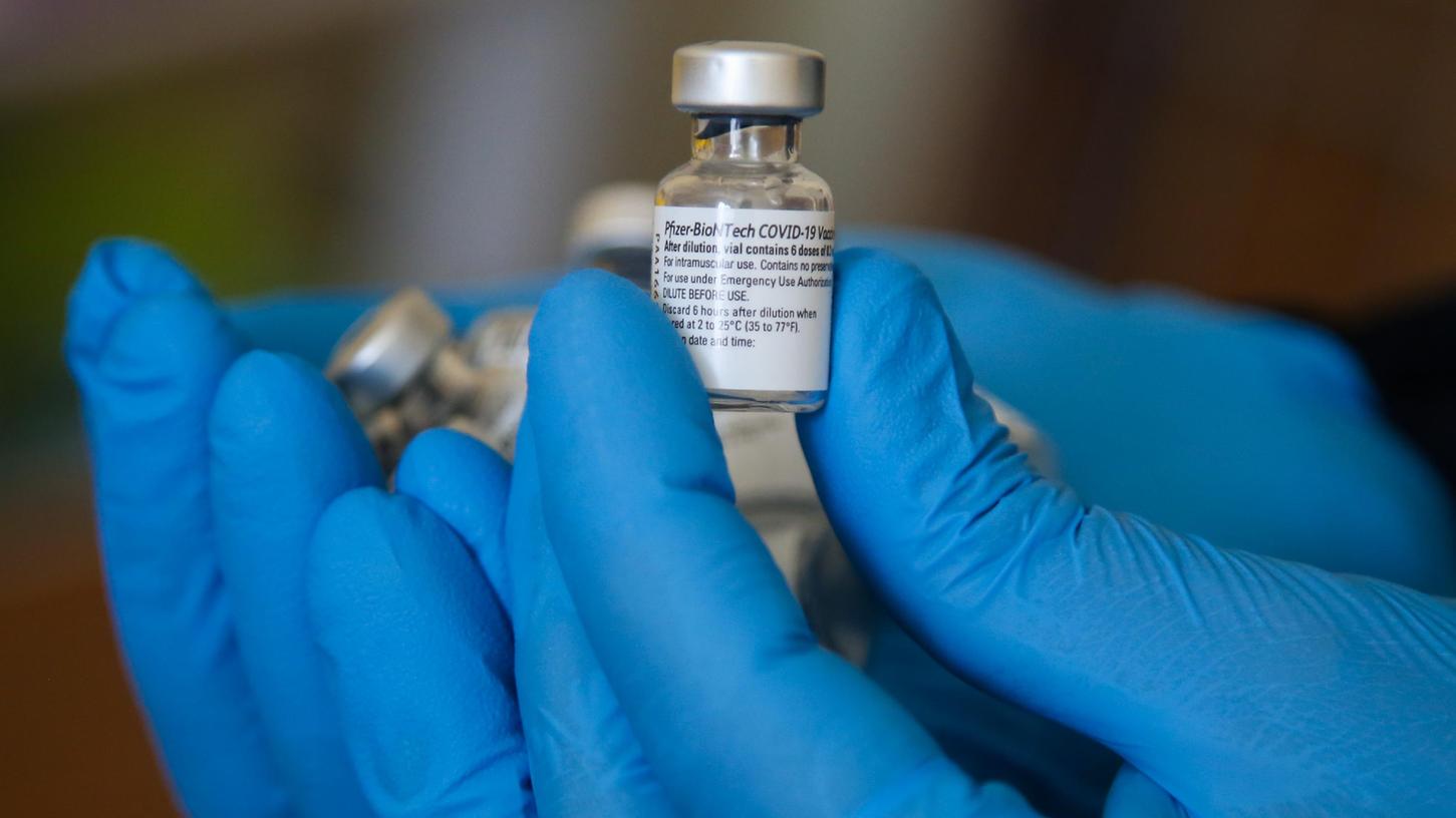 Ein Impfarzt hält einen Behälter mit dem Impfstoff gegen Covid-19 von Pfizer in einem Impfzentrum während der Impfung. Das Bamberger Impfzentrum ist in den letzten Tagen umgezogen. 