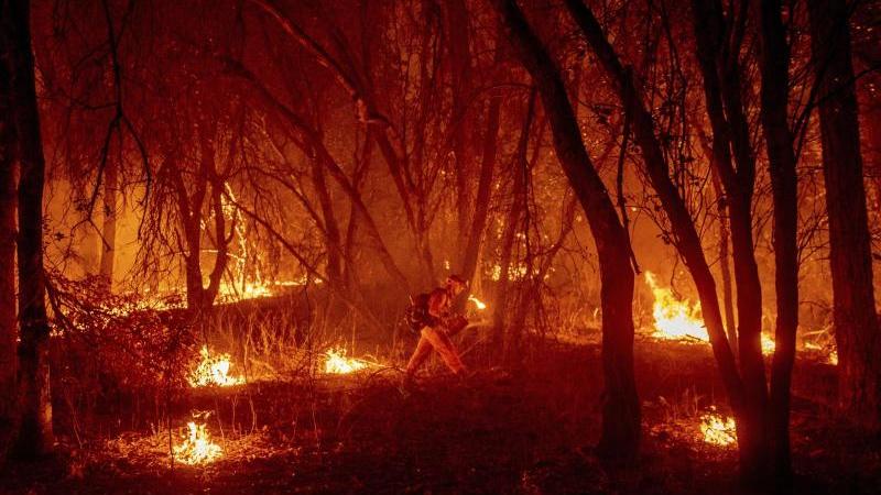 Ein Feuerwehrmann versucht, ein Feuer einzudämmen. Extremwetter werden jüngere Generationen immer häufiger treffen. 