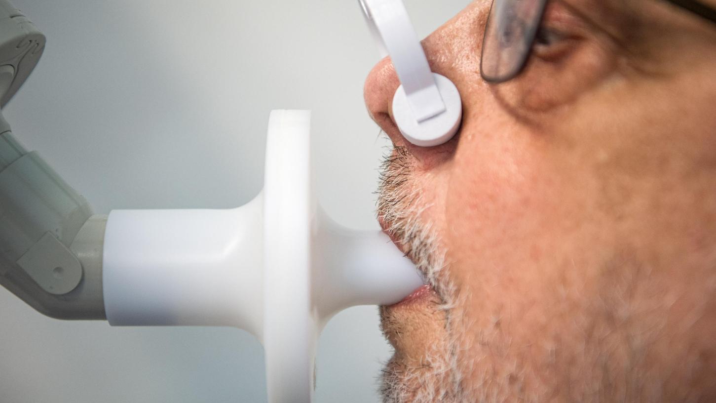 Ein Patient sitzt in einer Klinik am Teutoburger Wald, in der Long-Covid-Patienten behandelt werden, zur Überprüfung seiner Lungenfunktion in einem Bodyplethysmographen.