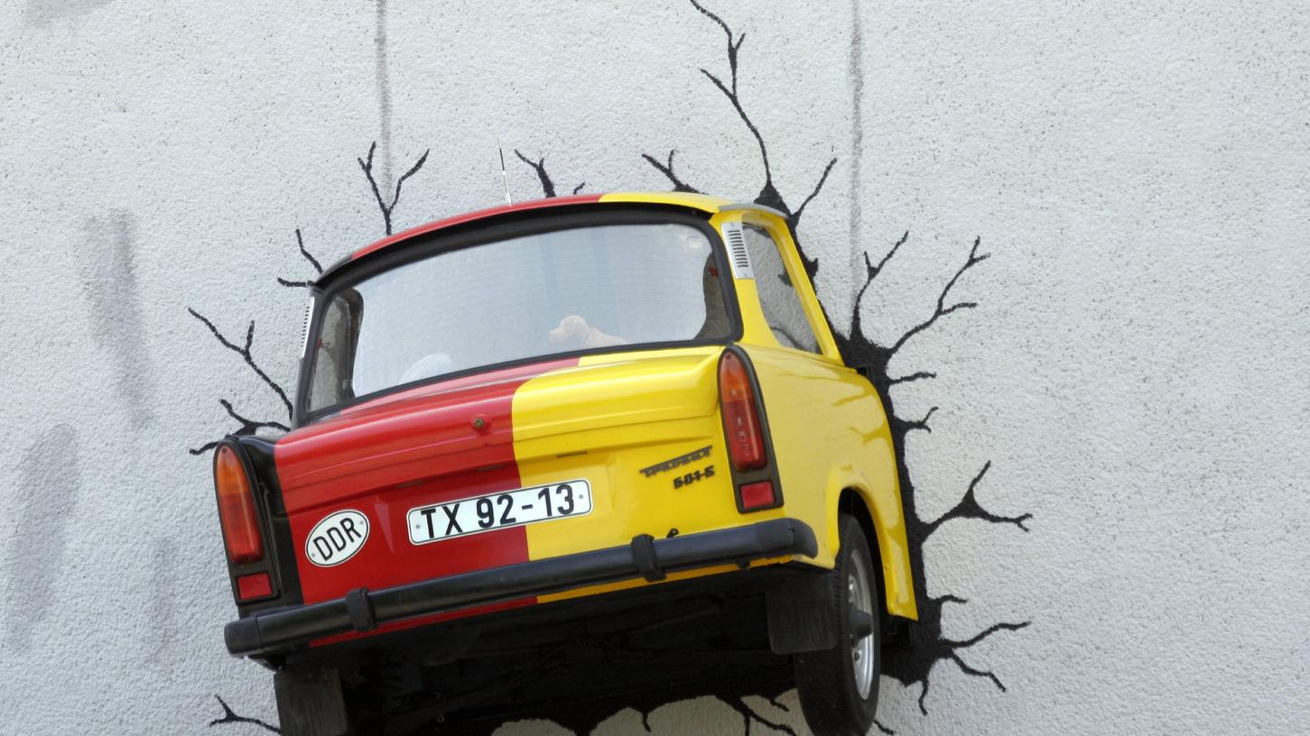 Deutsche Symbolwelt: Ein Trabbi mit Wackeldackel im Heck steckt in einer Wand. Totalschaden? Eine neue Nationalhymne täte dem seit 1990 vereinten Deutschland ebenfalls gut.