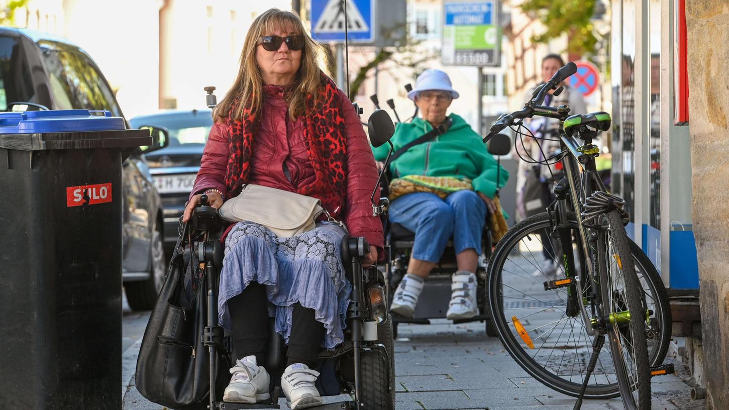 Monika Schmidt (li.) und Monika Reintges (re.) sind in der Forchheimer Hornschuchallee unterwegs: Als Rollstuhlfahrerinnen stoßen sie immer wieder auf Hindernisse und schmale Gehwege.
