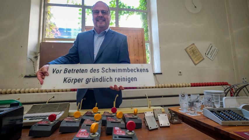 Bürgermeister Christian Vogel hält ein Schild, das bei den Erinnerungsstücken verkauft wird.