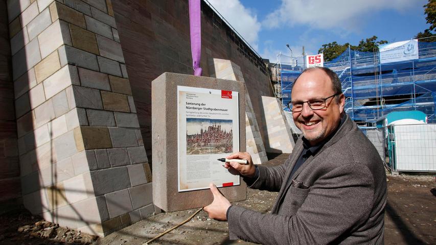 Bürgermeister Christian Vogel unterschreibt auf der Erinnerungsplatte, die anschließend in die Mauer eingesetzt wird.