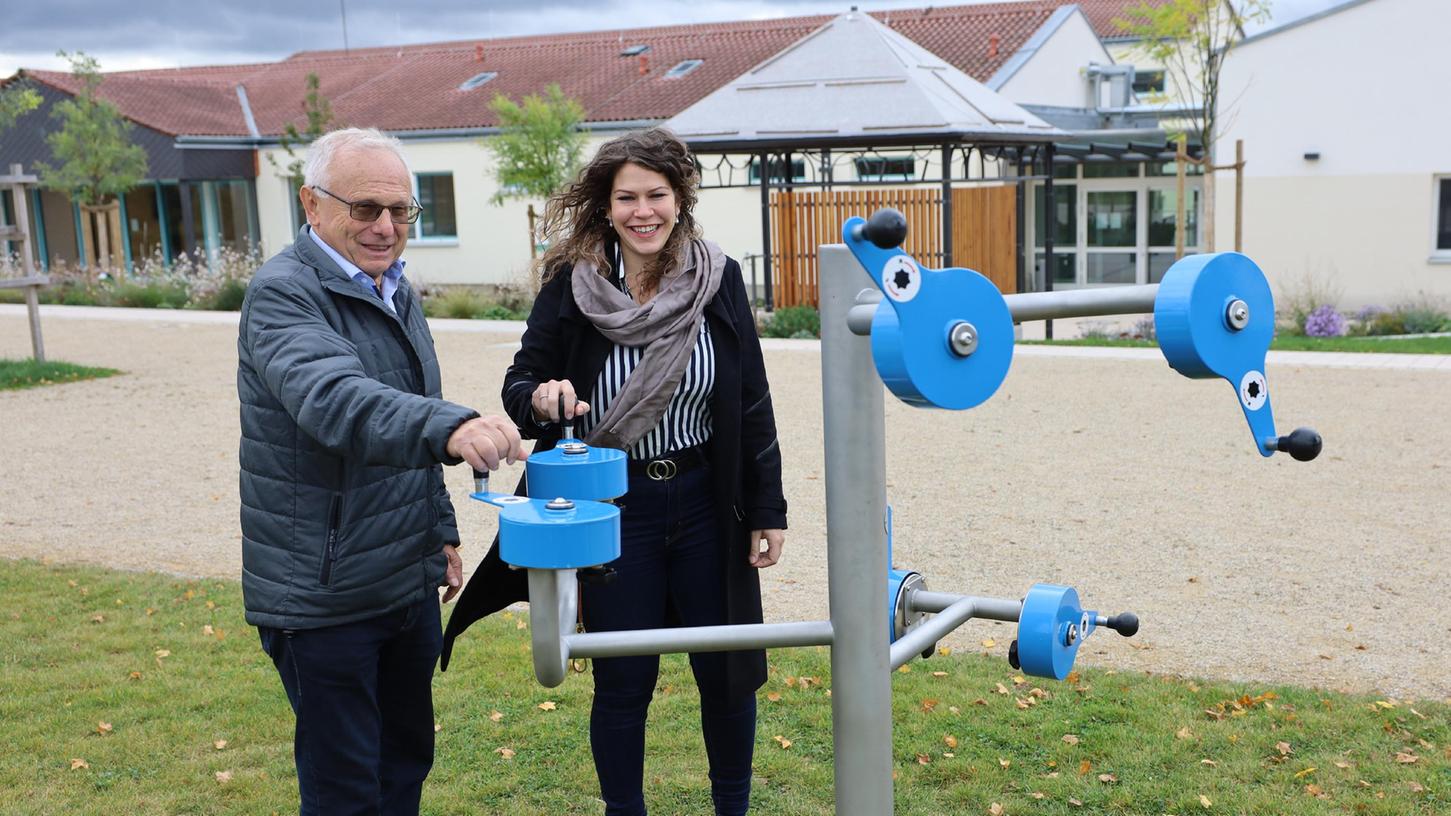 Helmut Lottes und Sofie Wedel zeigen, wie dieses Fitnessgerät auf dem Mehrgenerationenplatz funktioniert. Im Hintergrund ist das Haus der Begegnung zu sehen. Helmut Lottes und Sofie Wedel zeigen, wie dieses Fitnessgerät auf dem Mehrgenerationenplatz funktioniert. Im Hintergrund ist das Haus der Begegnung zu sehen.