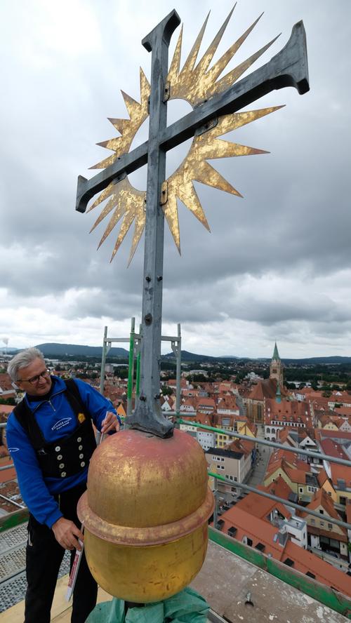 Über der Hofkirche an der Turmspitze: das Kreuz mit Strahlenkranz.