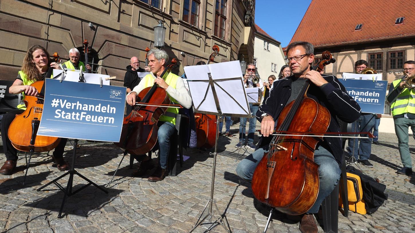 Orchestermusiker aus ganz Bayern sowie Thüringen und Baden-Württemberg musizieren während eines Flashmobs hinter Plakaten, auf denen Orchestermusiker aus ganz Bayern sowie Thüringen und Baden-Württemberg musizieren während eines Flashmobs hinter Plakaten, auf denen