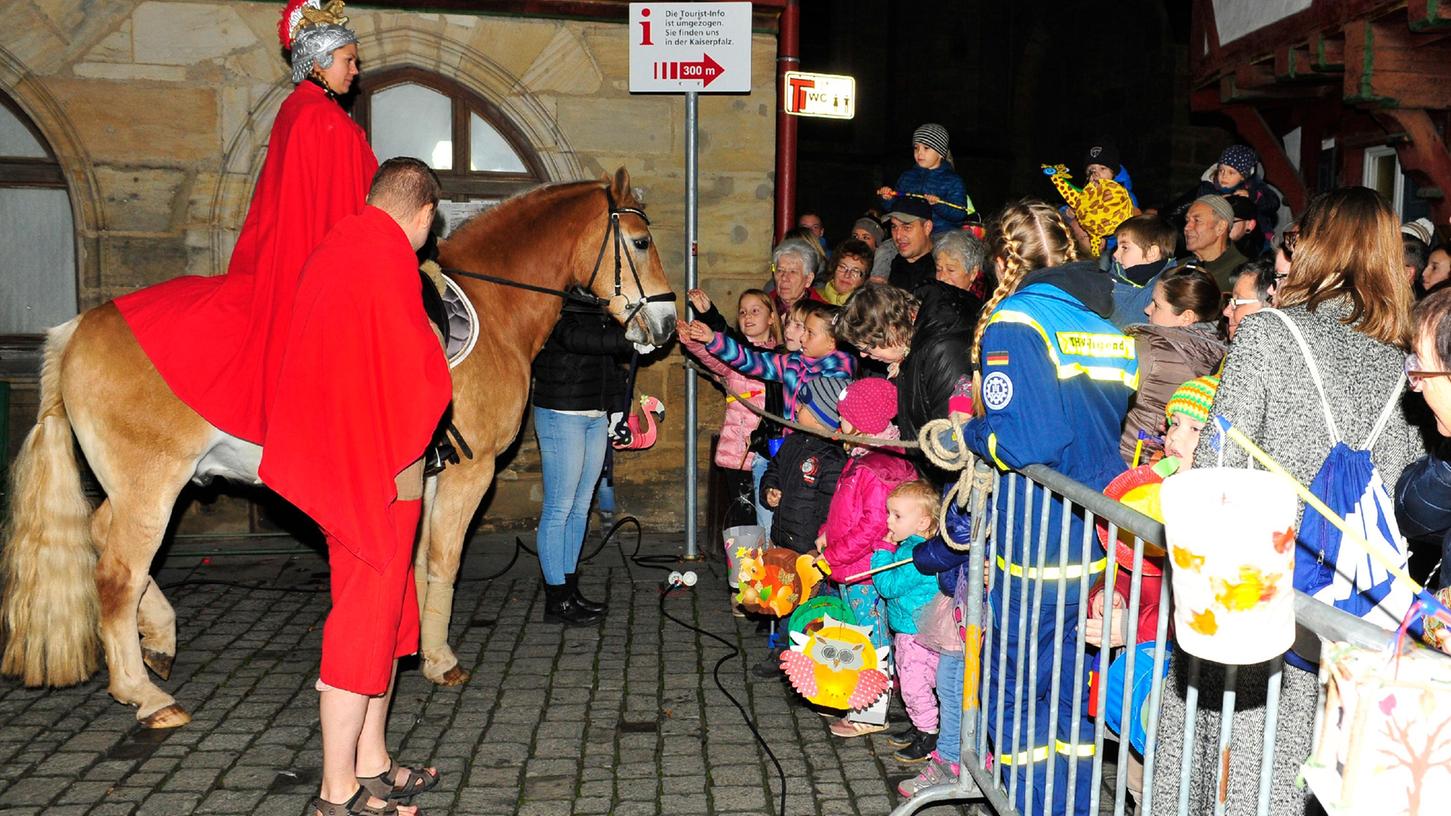 Der Forchheimer Martinsritt 2018. Dicht gedrängt stehen Kinder mit ihren Laternen und Familien an der Absperrung. In Sandalen der Bettler, gespielt vom Kolpingbruder Josua Flierl.