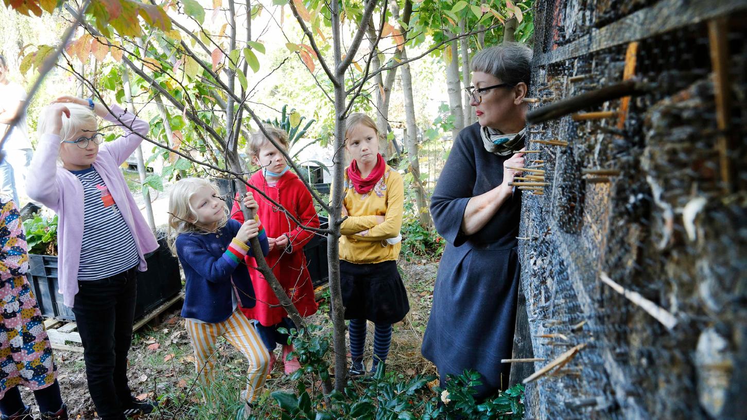 Die pädagogische Workshopleiterin Xenia Mohr (re.) zeigt den kleinen Besuchern die fest installierten Insektenhotels im Stadtgarten.