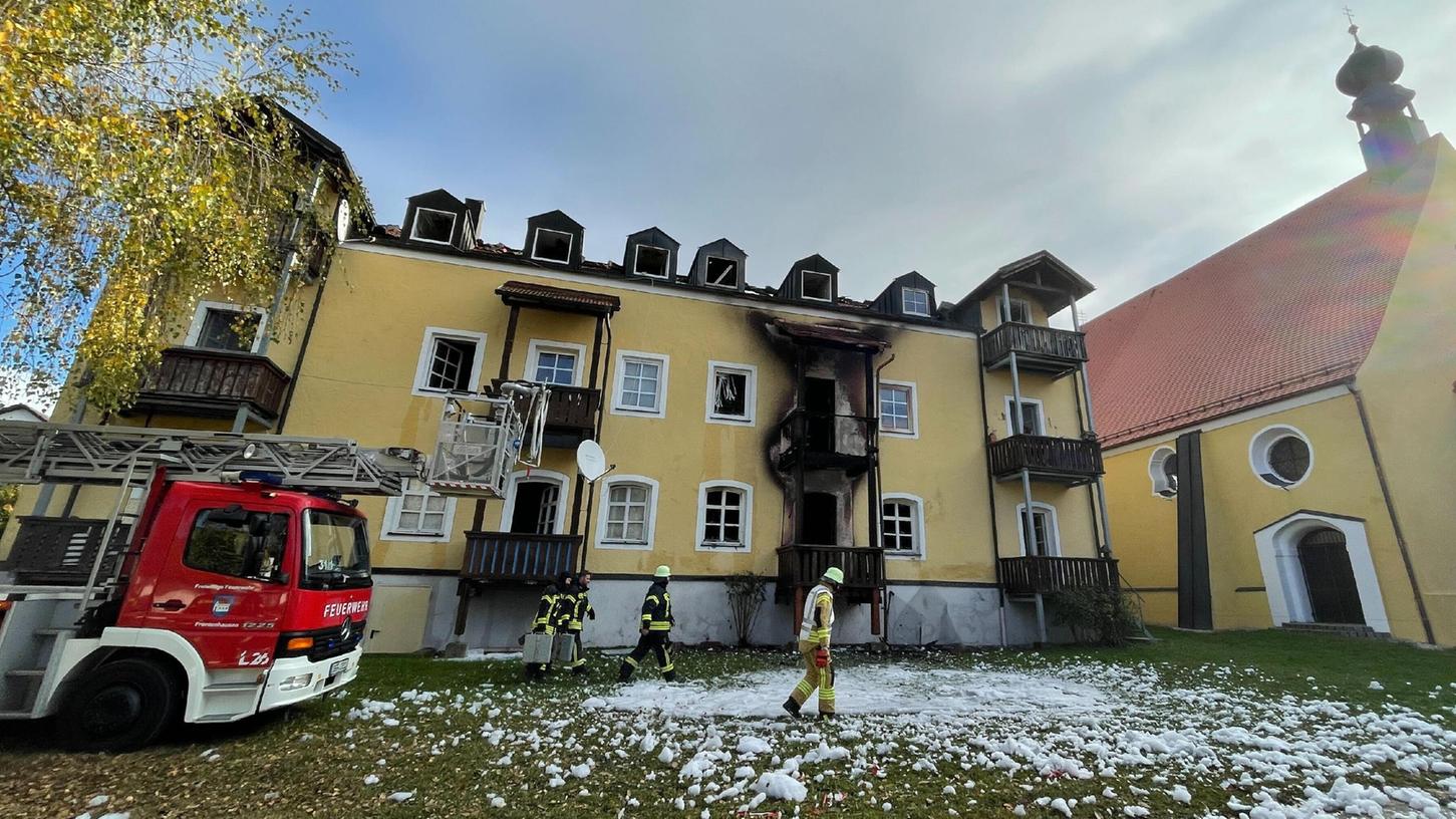 Bayern, Reisbach: Feuerwehrleute stehen vor einem Haus in Reisbach im niederbayerischen Landkreis Dingolfing-Landau.. Drei Frauen und ein frühgeborenes Baby sind hier bei einem Brand ums Leben gekommen.
