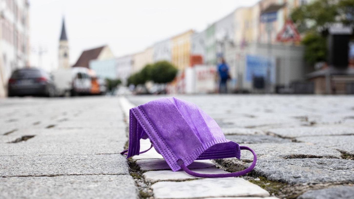 Eine violette medizinische Maske liegt auf einer Straße. Das Gesundheitsamt Weißenburg-Gunzenhausen empfiehlt, bei Zusammenkünften in Innenbereichen weiterhin das Tragen einer FFP2- oder medizinischen Maske.