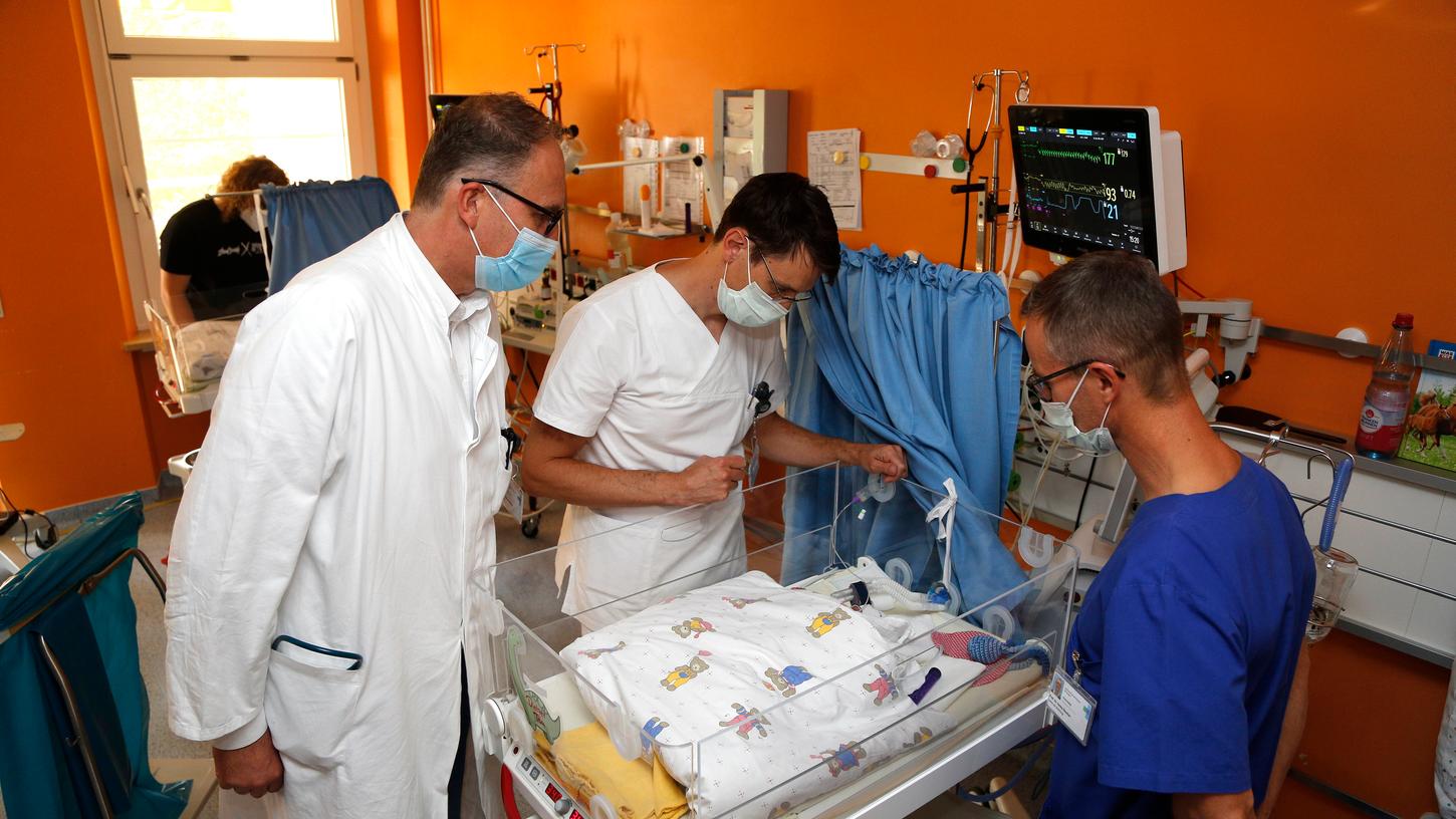 Prof. Dr. Joachim Wölfle, Direktor der Kinder- und Jugendklinik am Uniklinikum Erlangen, Dr. Patrick Morhart und Prof. Dr. Heiko Reutter (von links) schauen nach einem Frühchen im Inkubator.