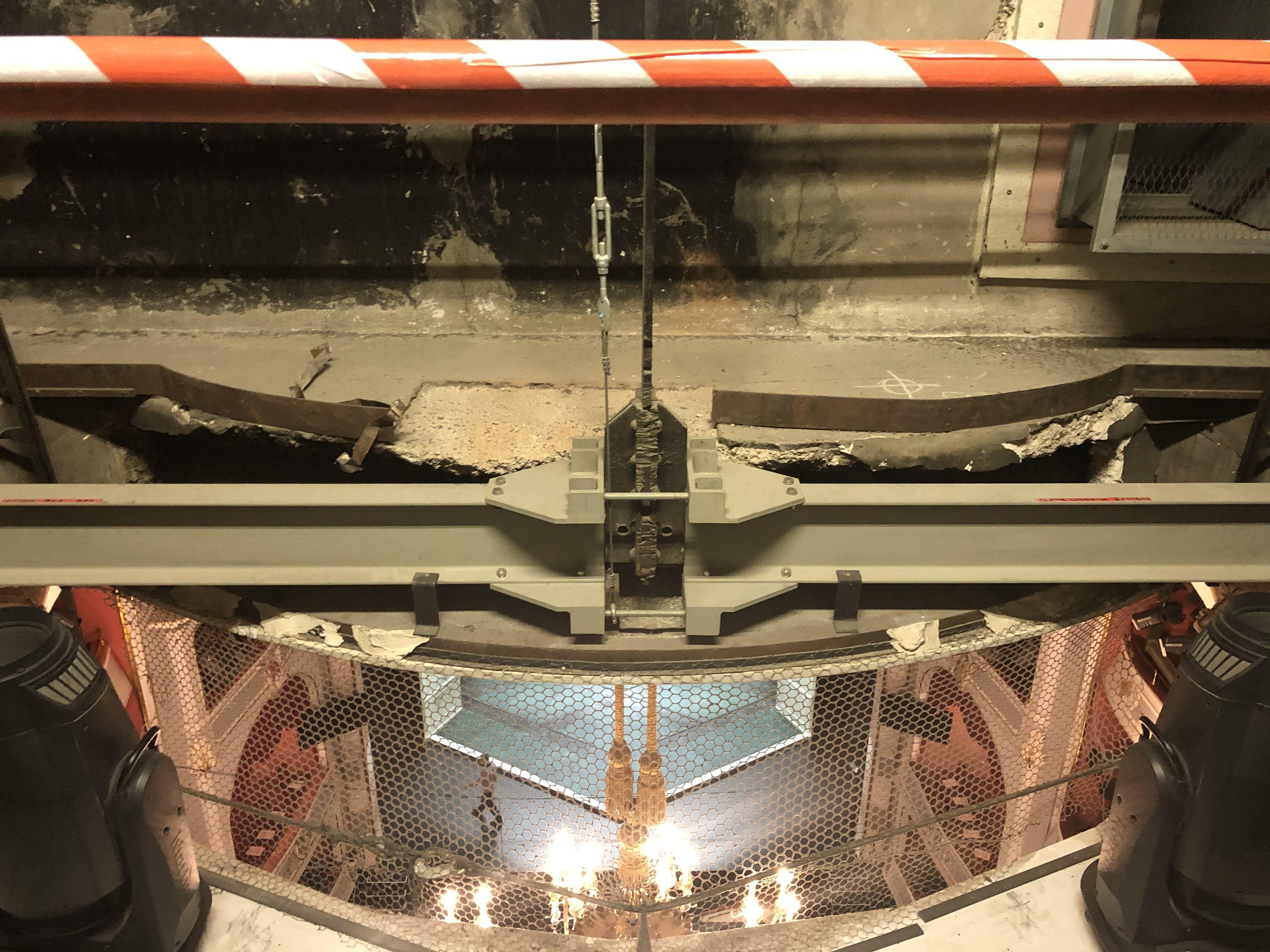 Diese Durchsicht vom Dachboden auf die Bühne offenbart ihre Dramatik nicht von selbst. In der oberen Bildhälfte ist die Befestigung des Kronleuchters zu erkennen. Ein entscheidender Stahlträger wurde dafür bei den Umbauten in der NS-Zeit zerschnitten, später provisorisch wieder stabilisiert. Die damals abgehängte Saaldecke droht jetzt auf die heutige Decke zu stürzen.