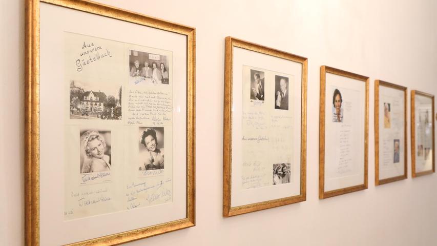 Im Erdgeschoss hängen Bilderrahmen mit Fotos und Unterschriften an der Wand, die zeigen, welche prominenten Gäste schon zu Besuch waren: Darunter...

