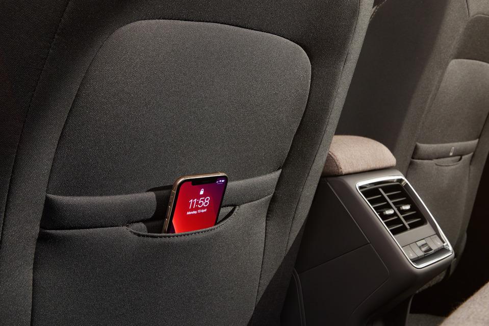 Praktisches Detail: Smartphone-Tasche in den Rückenlehnen der Vordersitze. Auch eine Halterung gibt es, so dass das Handy als Unterhaltungsprogramm fungiert.