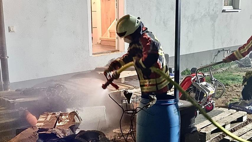 Ein Feuerwehrmann löscht das Brandgut im Freien.