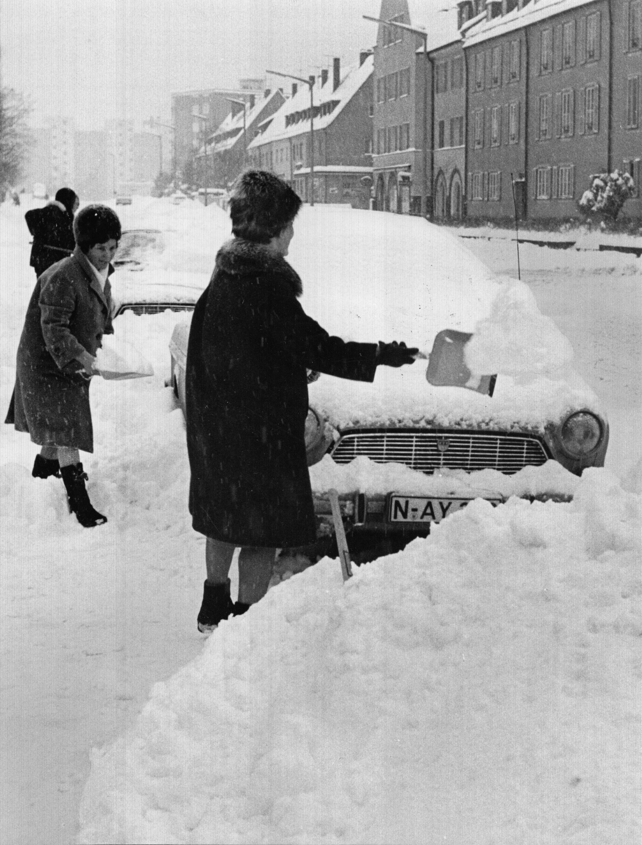 Mit Schaufel und Besen versuchten diese Autofahrerinnen, ihre Fahrzeuge zu befreien. Oft waren die Autos so von Schneebergen umgeben, dass sie kaum freizubekommen waren.
