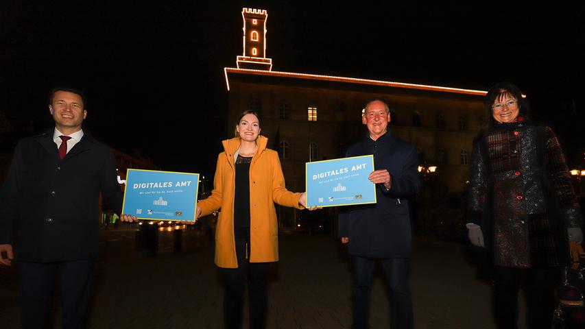 Vor der Kulisse des weihnachtlich beleuchteten Fürther Rathauses nahmen OB Thomas Jung, Landrat Matthias Dießl und Fürths Kämmerin Stefanie Ammon die Plaketten aus den Händen von Digitalministerin Judith Gerlach (2.v.li.) entgegen.