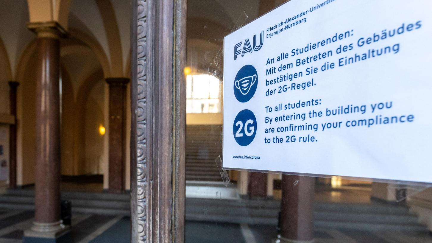 Ein Zettel weist an einer Eingangstür der Friedrich-Alexander-Universität Erlangen-Nürnberg (FAU) auf die Einhaltung der 2G-Regel hin. 