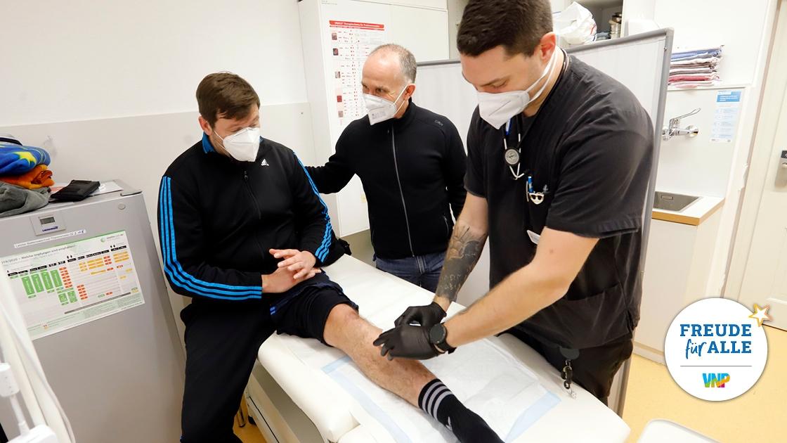 Patrick Phillips (re.) und Roland Stubenvoll (Mi.) versorgen Stefan L., der wegen einer gefährlichen Entzündung am Bein behandelt werden musste.