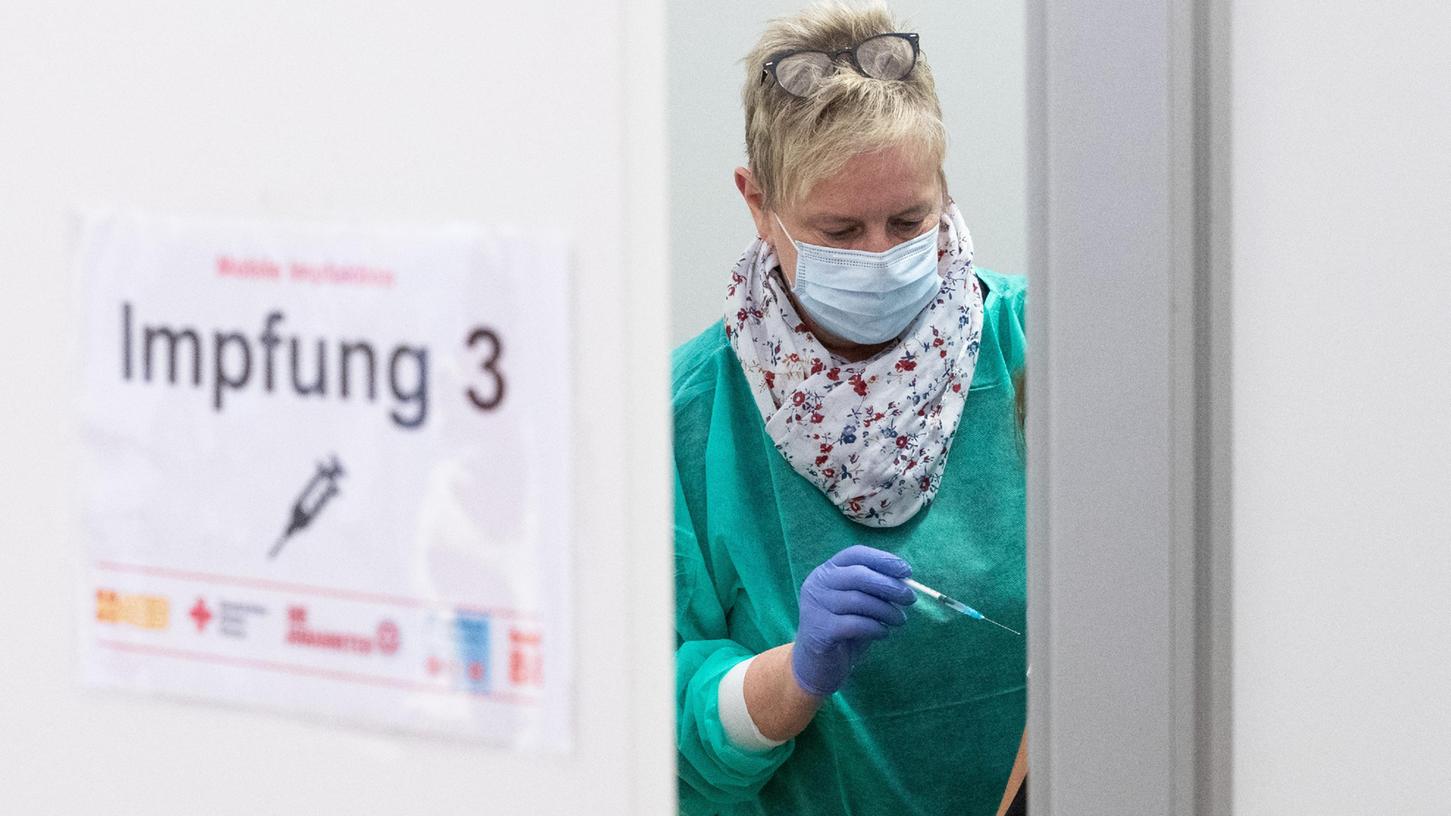 Eine Arzthelferin hält eine Spritze bereit zur Booster-Impfung in einem Impfzelt. Die Auffrischungsimpfungen laufen in Bayern inzwischen auf Hochtouren, allerdings hat die Anmeldung für einen Termin in einem Impfzentrum seine Tücken.