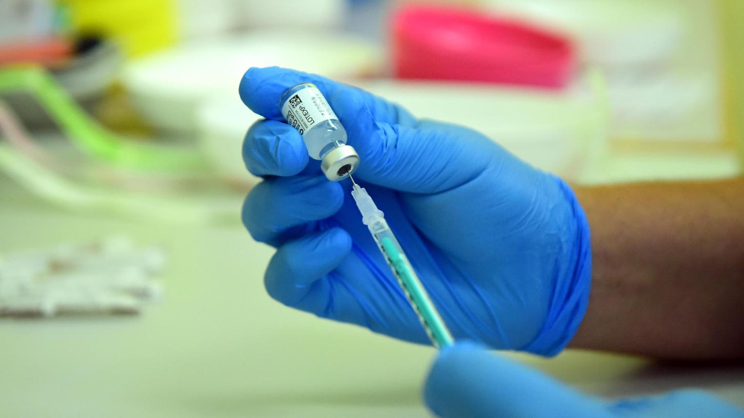 Ein Impfhelfer zieht eine Spritze mit dem Vakzin von Biontech auf. 