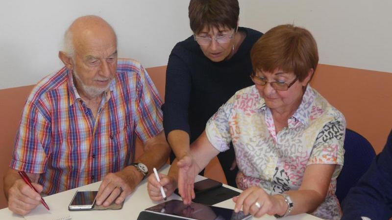 Digital-Botschafterin Birgitt Pfirrmann (M) zeigt im Seniorenbüro Landau Kniffe im Umgang mit einem Tablet.
