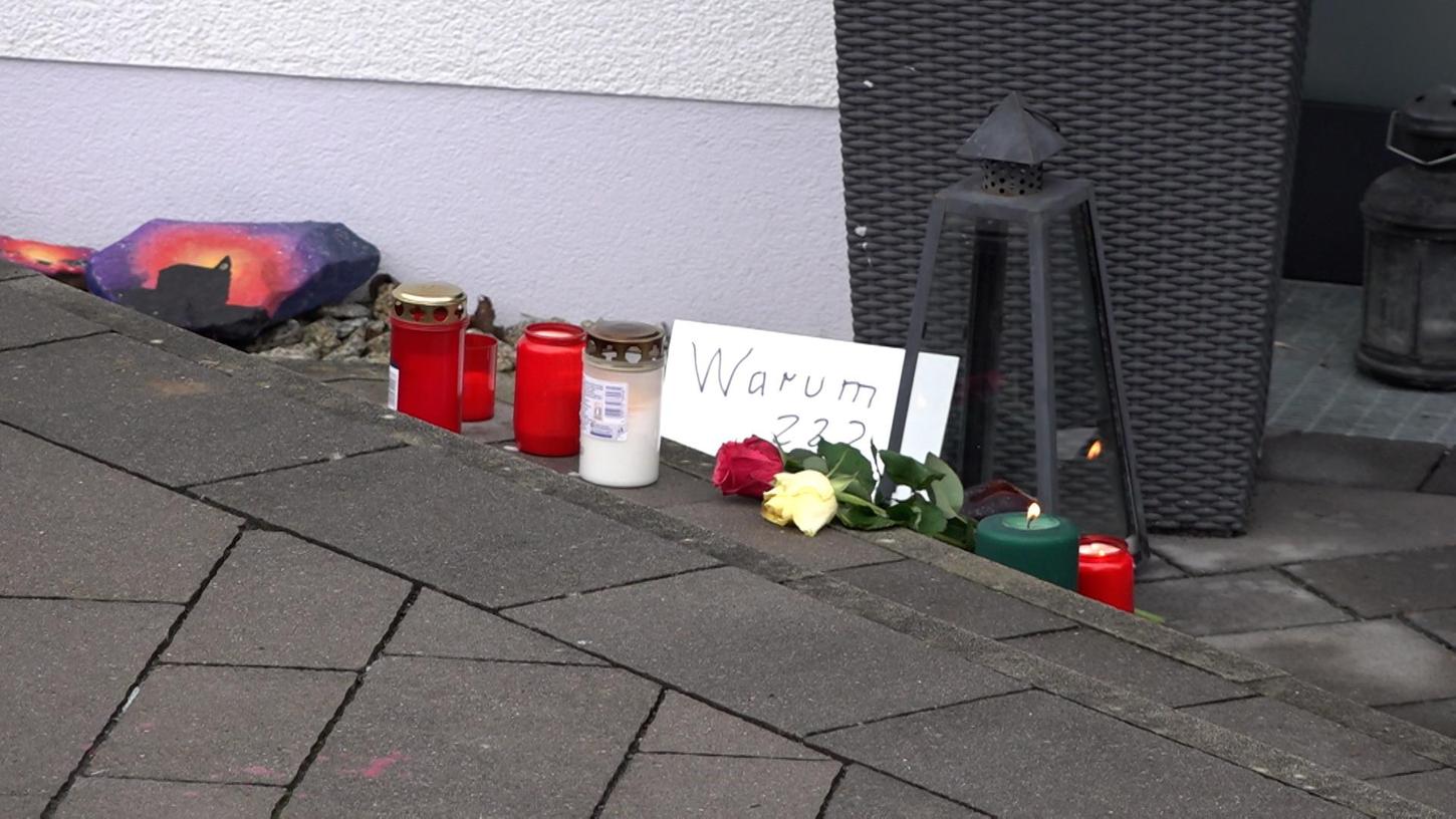 Vor der Eingangstür des Wohnhauses im oberfränkischen Mistelbach haben Anwohner Blumen und Kerzen hinterlegt. In der Nacht zum Sonntag wurden Vater und Mutter von vier Kindern im Keller des Hauses erstochen aufgefunden.
