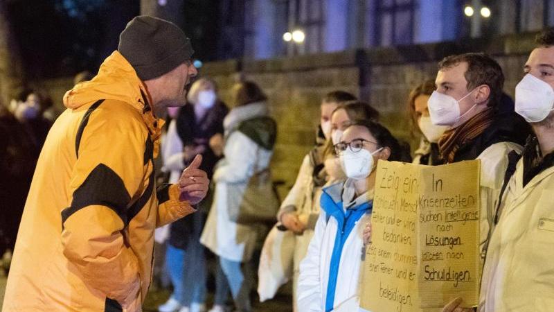 Ein Teilnehmer einer als "Spaziergang" deklarierten Demonstration von Impfgegnern und Kritikern der Corona-Maßnahmen steht am Universitätsklinikum Dresden vor zahlreichen Gegendemonstranten.