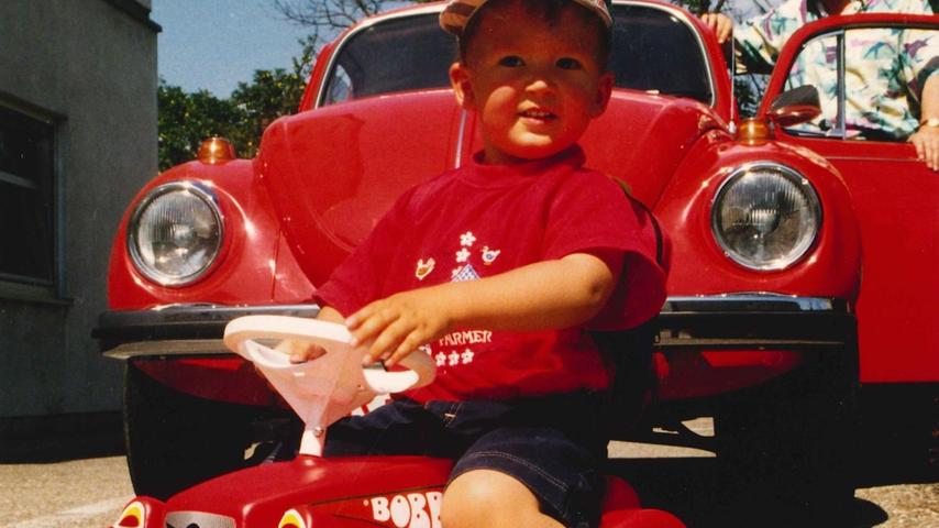 Zwei Kultobjekte, zwei Generationen: Während der Junior stolz Bobby-Car fährt, rattert der Erwachsene mit seinem roten VW Käfer über die Straßen der Republik. 