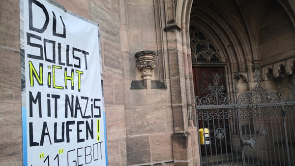 Das "Elfte Gebot" hängt als Plakat an der Kirche St. Peter in der Nürnberger Südstadt. Ein eindeutiger Seitenhieb gegen die Corona-Demonstrierenden: "Du sollst nicht mit Nazis laufen!"