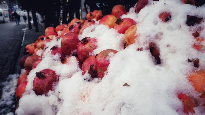 Ein Obsthändler bietet Granatäpfel an - unter einer dicken Schneeschicht mitten in Istanbul.