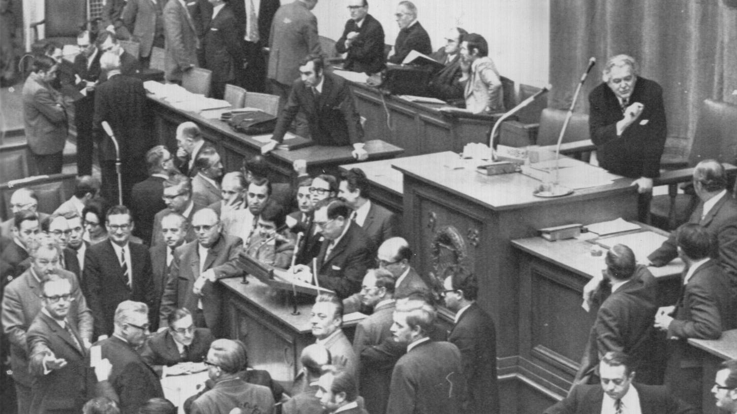 1971 wurde im Bayerischen Landtag erbittert über die bevorstehende Gebietsreform gestritten. Hier unterhält sich Landtagspräsident Hanauer (am Mikrofon) mit SPD-Landeschef Gabert. Im Vordergrund warten Parlamentsmitglieder auf das Ergebnis der Abstimmung.
