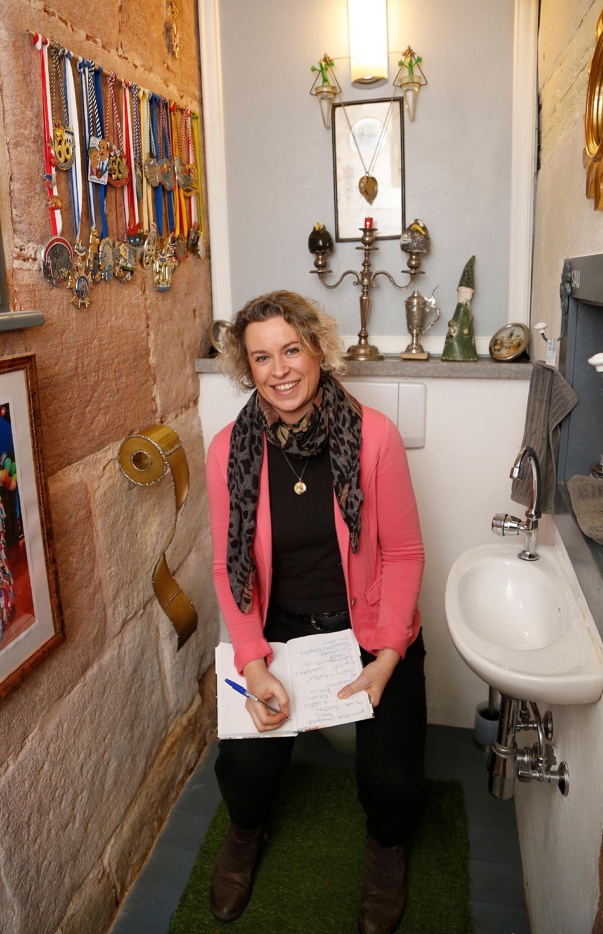 Zum Schluss macht auch Redakteurin Anette Röckl noch einen Witz und posiert mit Schreibwerkzeug auf dem Lokus. Auf die güldene Klopapierrollen-Skulptur fallen übrigens viele immer herein, freut sich der Hausherr.