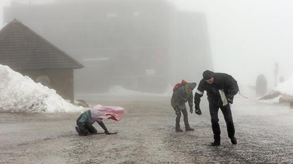 Sachsen-Anhalt, Schierke: Wanderer auf dem Brocken schützen sich vor starken Windböen.