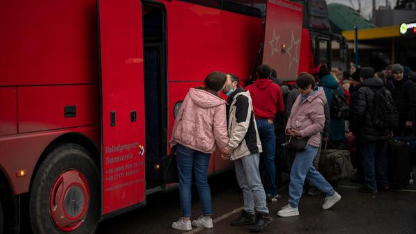 Ein Paar küsst sich zum Abschied, bevor die Frau einen Bus besteigt, um die Stadt zu verlassen.