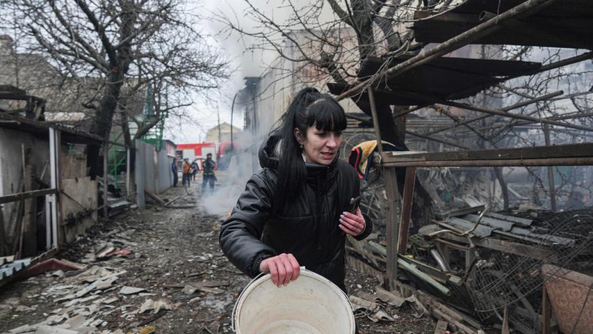 Eine Frau geht an den Trümmern nach russischem Beschuss vorbei. 