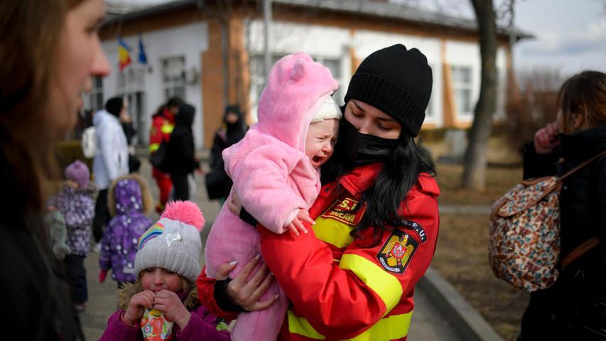 Eine Mitarbeiterin der Aufsichtsbehörde für Notfallsituationen beruhigt das weinende Baby einer Familie, die vor dem Konflikt in der benachbarten Ukraine an die rumänisch-ukrainische Grenze geflohen ist. 
