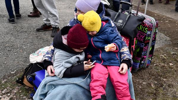 Eine Frau umarmt zwei Kinder an einem von örtlichen Freiwilligen betriebenen Kontrollpunkt, nachdem sie vor dem Konflikt in der Ukraine geflohen sind.