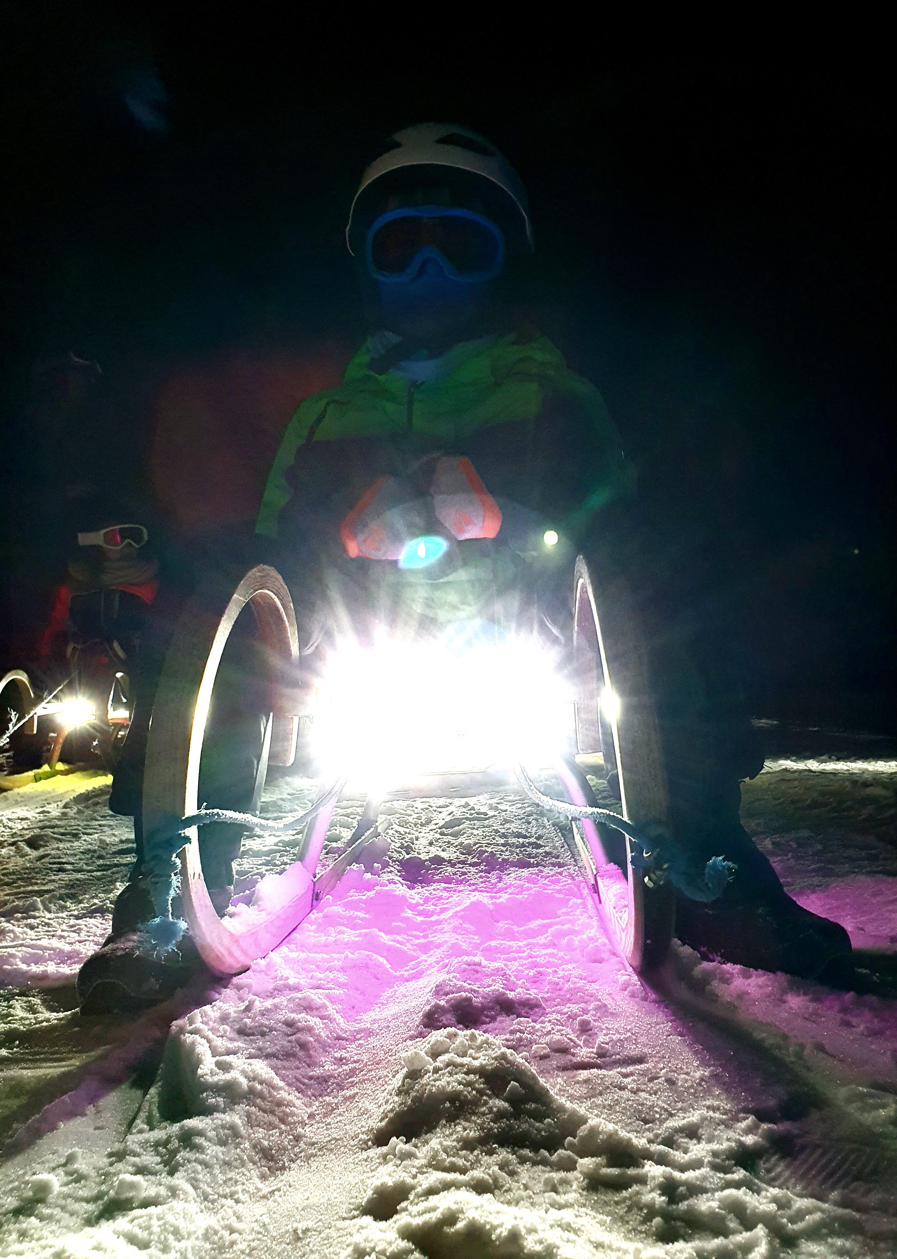 Lampen unter den Rodeln leuchten nachts die Schlittenbahn aus.