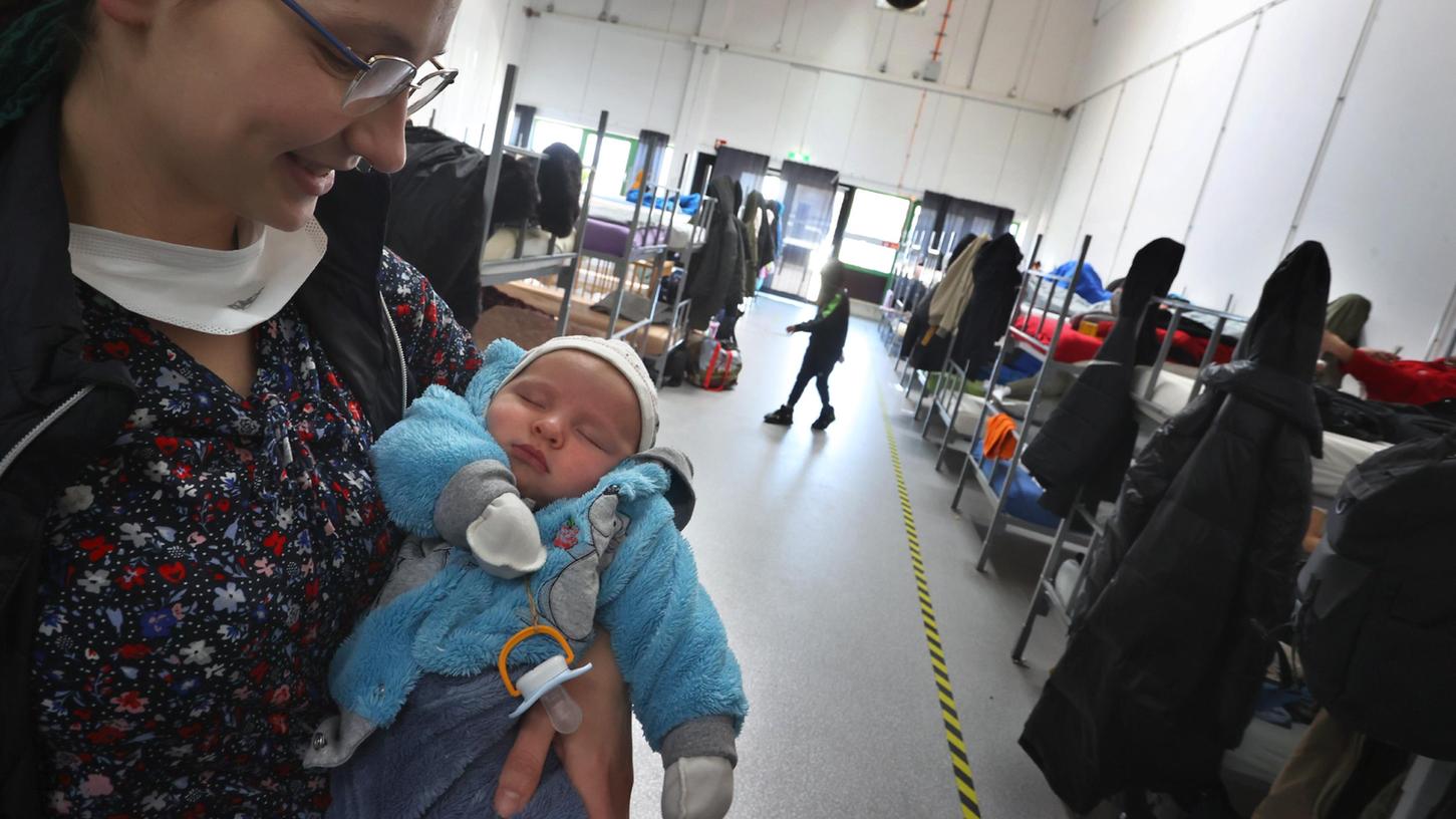  Eine geflüchtete Frau aus der Ukraine hält im Schlafsaal des Anker-Zentrums in Augsburg  ihr vier Wochen altes Baby auf dem Arm. 