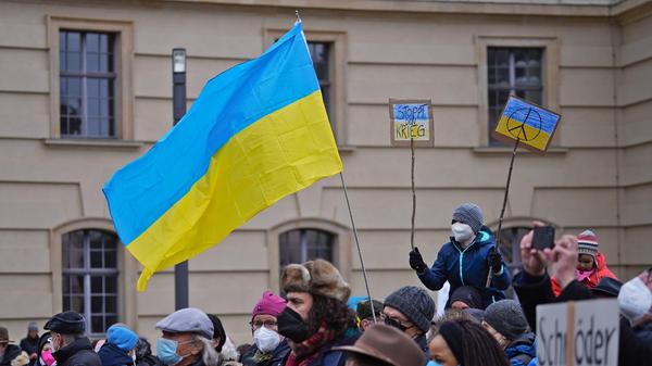 Protestierende gegen Putins Krieg mit ukrainischer Flagge Demonstration gegen Putins Krieg und den Überfall auf die Ukr