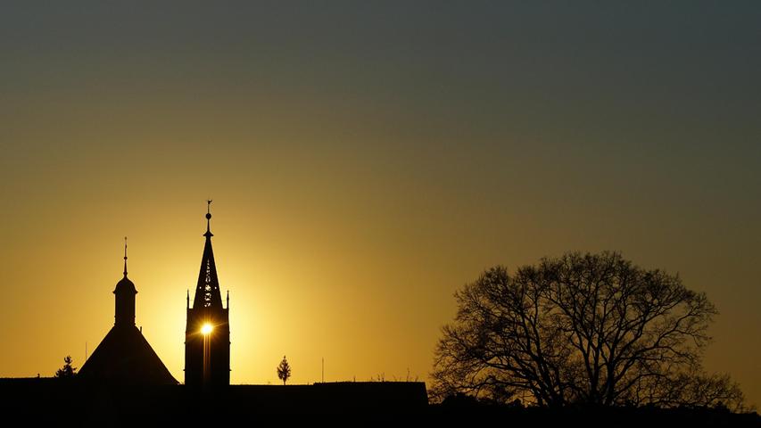 Sonnenuntergang in Heilsbronn: Die Sonne scheint direkt durch den Dachreiter des Münsters, daneben der Katharinenturm.