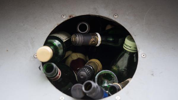 Sie dürfen mit Deckel in den Container. In der Sortiermaschine wird das Aluminium vom Glas getrennt und kann gesondert recycelt werden. Ausspülen ist auch nicht nötig, da das Altglas sowieso gewaschen wird.